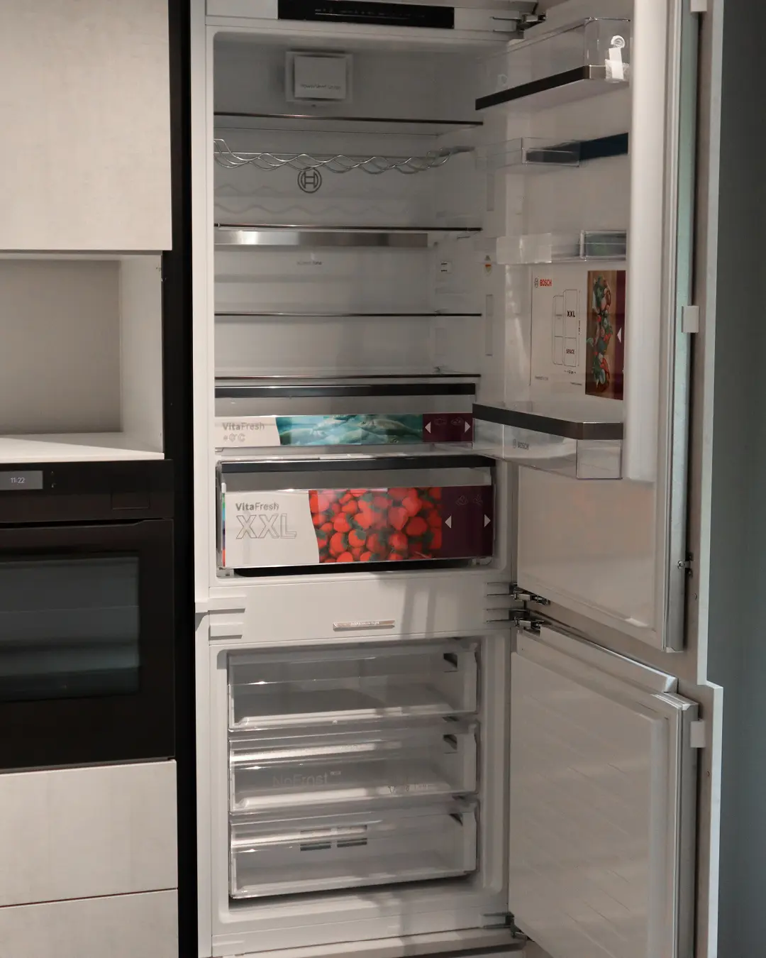Geöffneter Einbaukühlschrank von Bosch mit VitaFresh-XXL-Fach in der grifflosen Häcker Küche KSH3