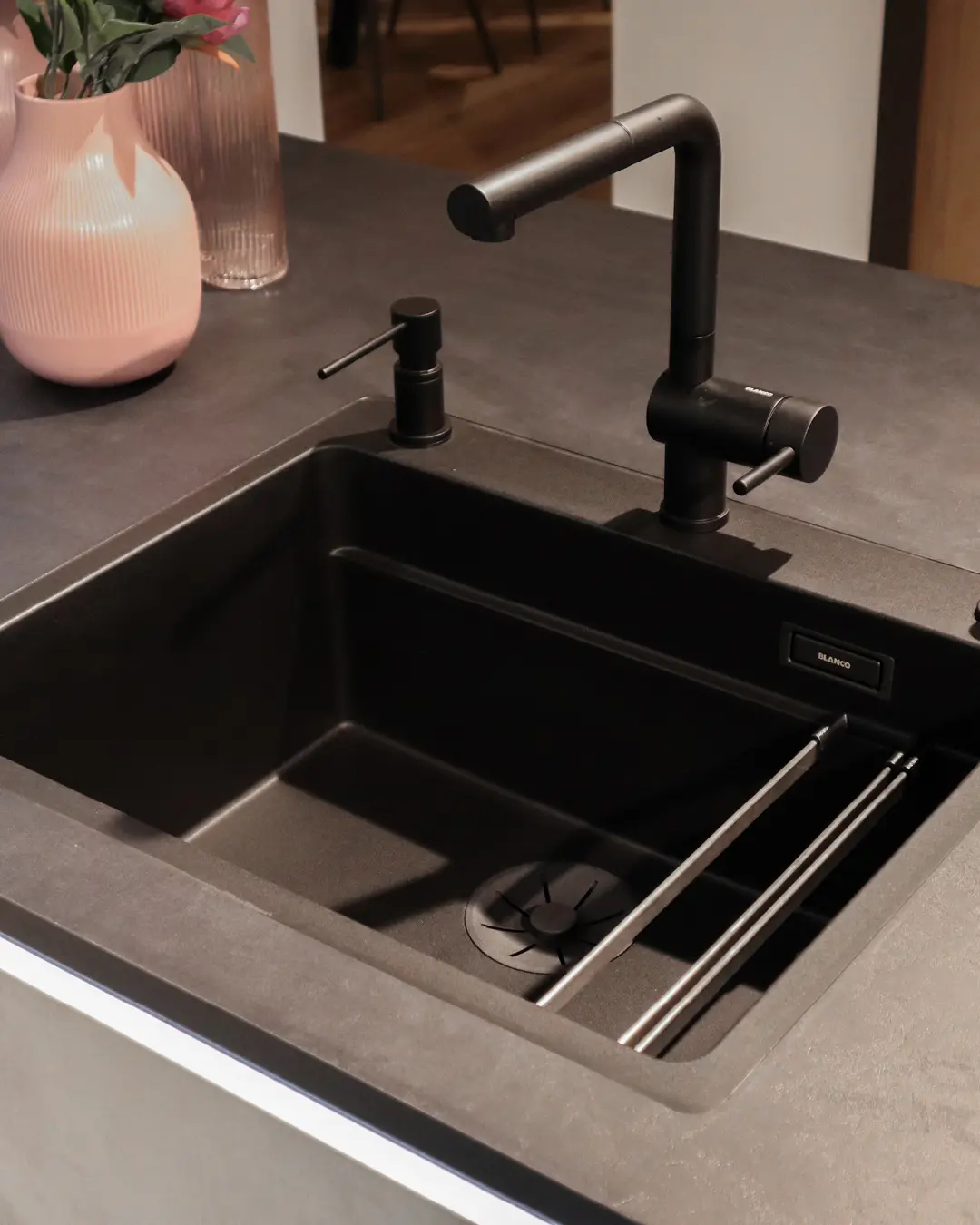 Schwarze Spüle mit Blanco Armatur und Seifenspender in der grauen grifflosen Häcker Küche in L-Form