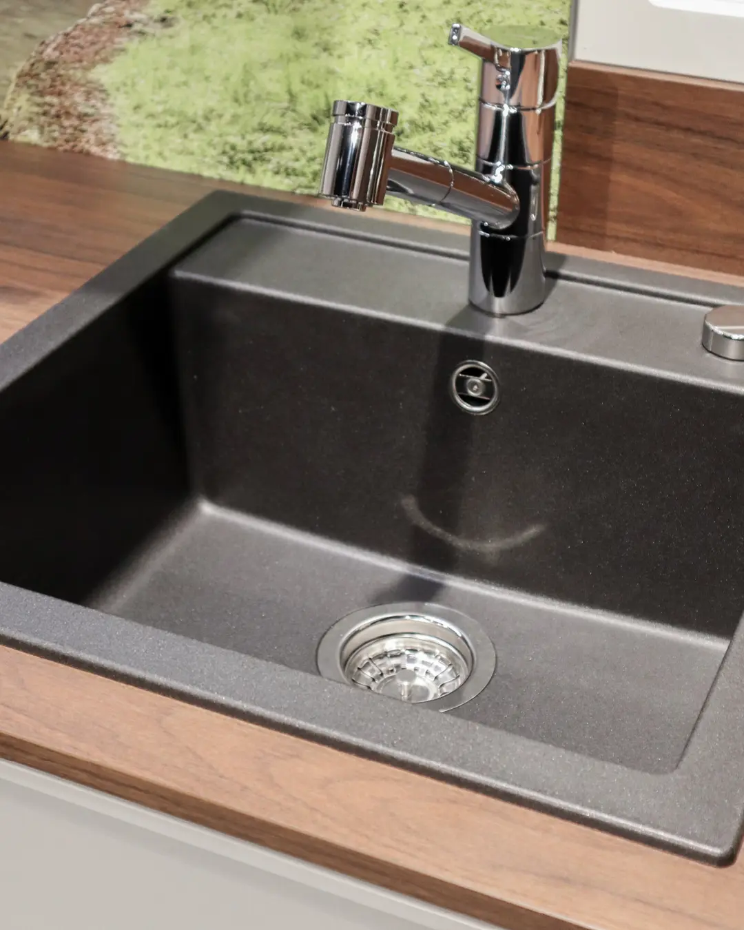 Dunkelgraue Einbauspüle mit Chromarmatur in Arbeitsplatte in Holzoptik der grauen Nobilia-Küche in G-Form