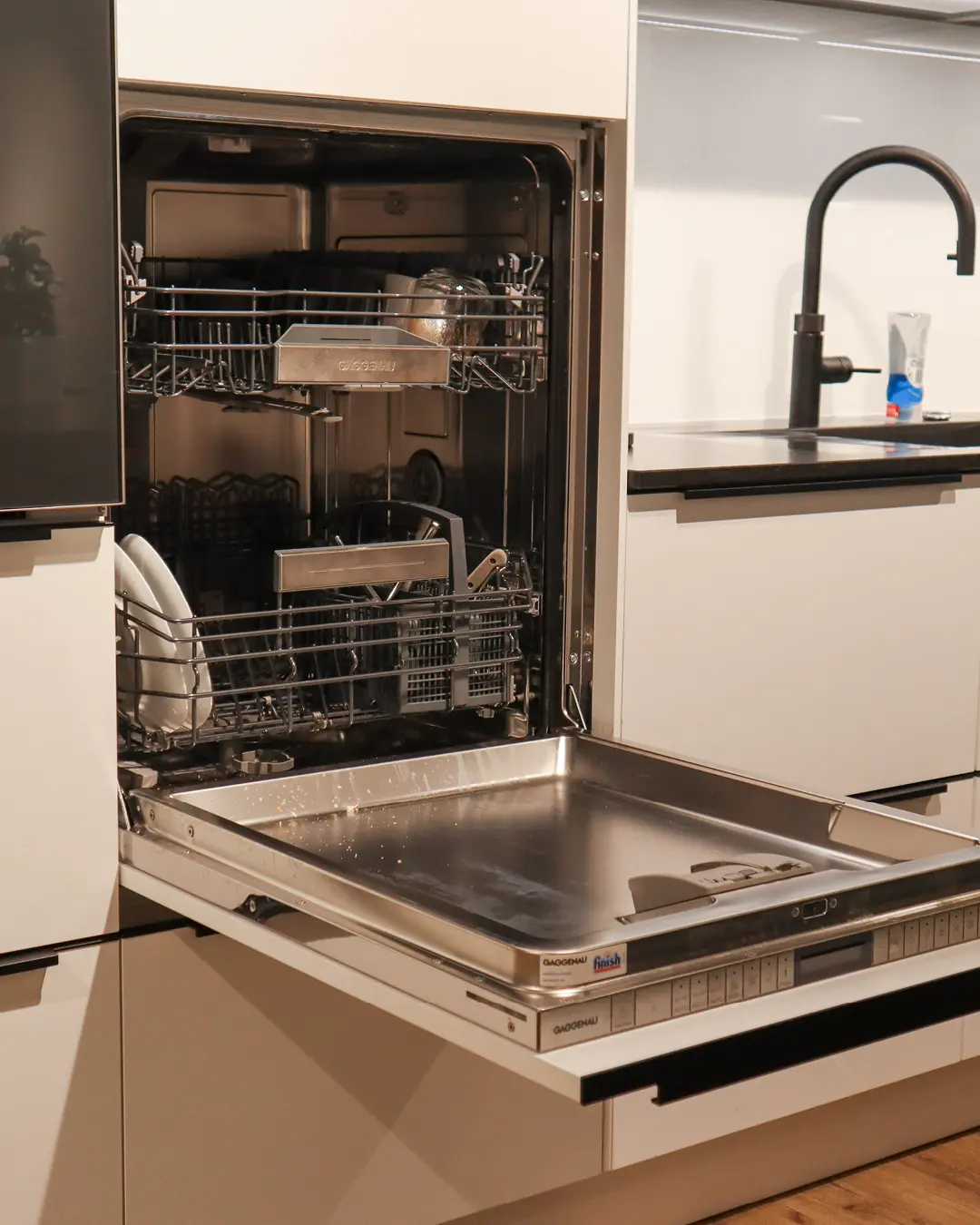 Geöffneter integrierter Gaggenau-Geschirrspüler in der kristallweißen Häcker Küche mit Kochinsel KSH7