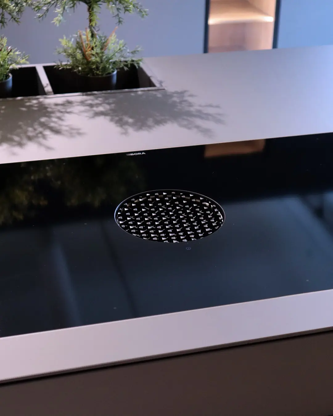 Detail der Kochinsel einer carbongrauen Leicht Küche mit rundem BORA-Muldenlüfter im schwarzen Kochfeld