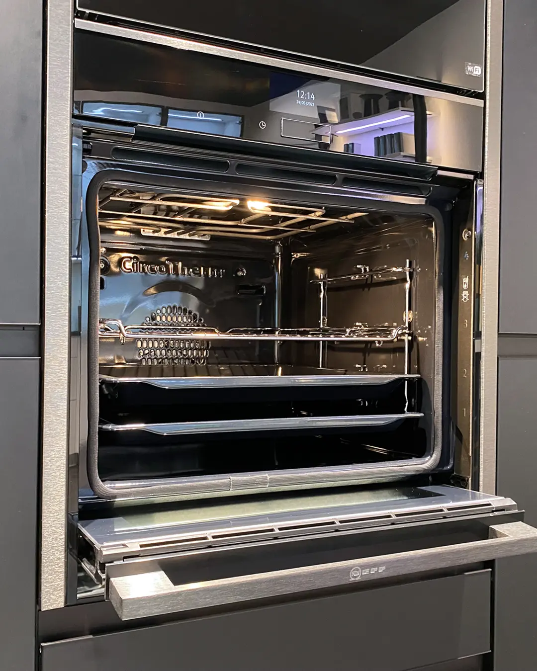 Geöffneter Neff-Einbaubackofen mit CircoTherm-Innenraum und Backblechen in der Nobilia Küche in L-Form