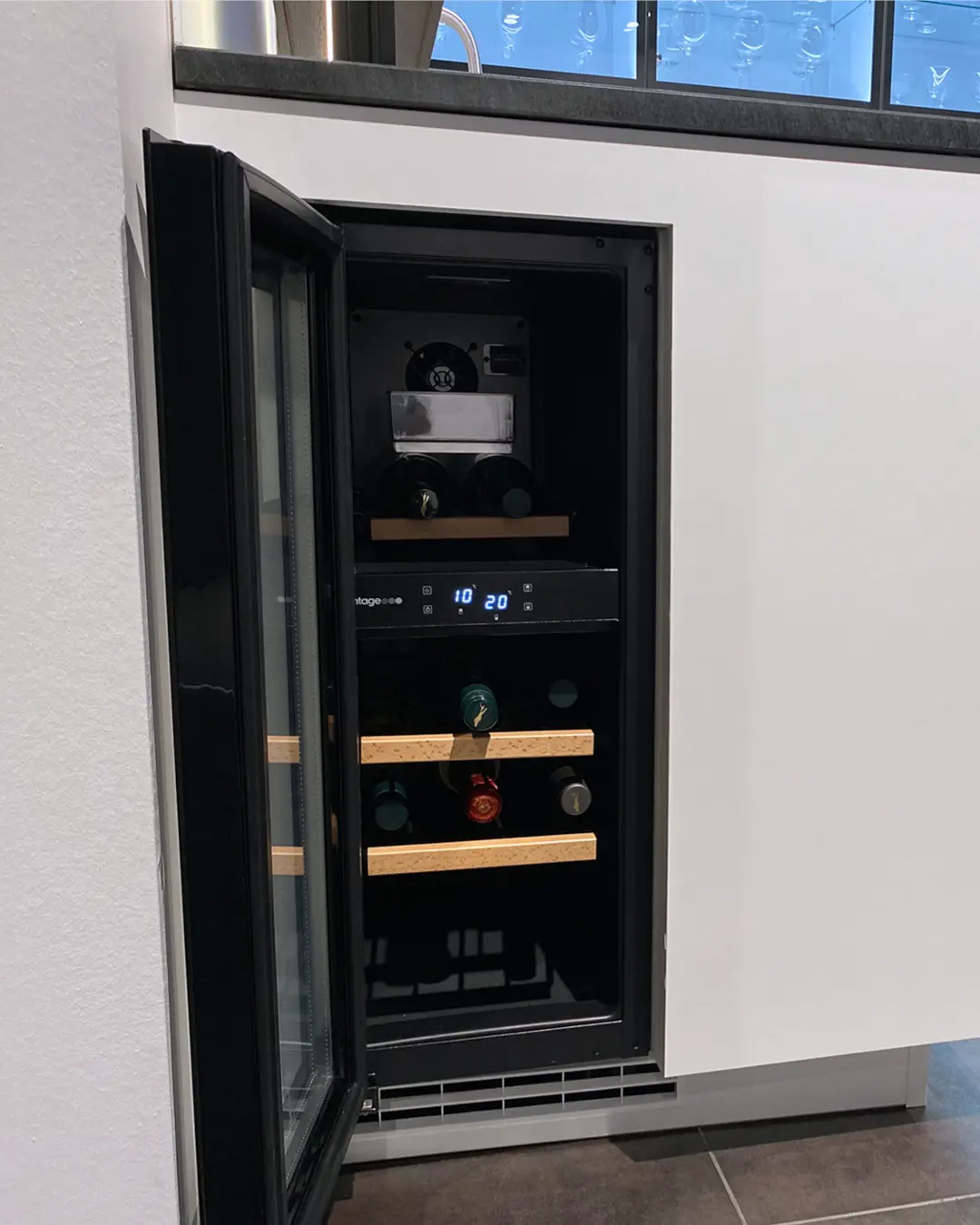 Geöffneter Einbau-Weinkühlschrank mit Holzauszügen in der matt-weißen Nobilia Küche KSD13 in L-Form