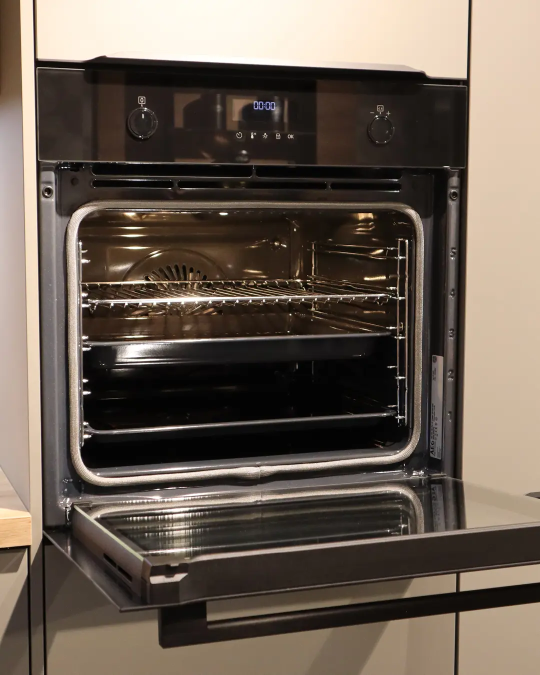 Geöffneter schwarzer Einbaubackofen mit Display und Rosten in der beige-grauen Nobilia Küche KSH14
