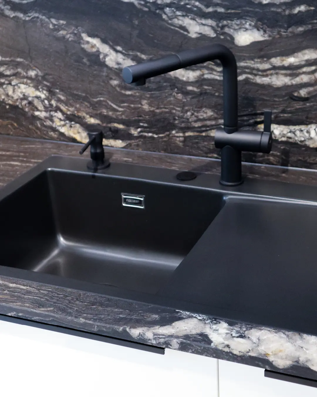 Schwarze Spüle mit schwarzer Armatur in Arbeitsplatte in Steinoptik der weißen Häcker Küche KBK17