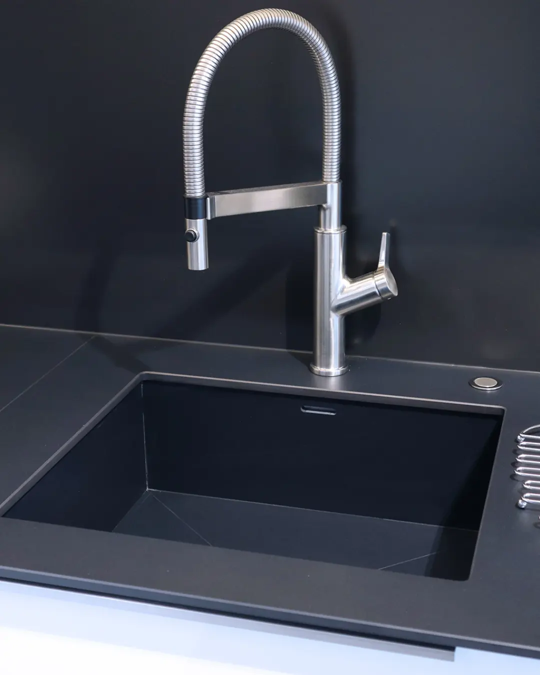 Detail der Häcker Küche KBK3: schwarze Unterbauspüle mit hoher Edelstahl-Profibrause vor dunkler Rückwand