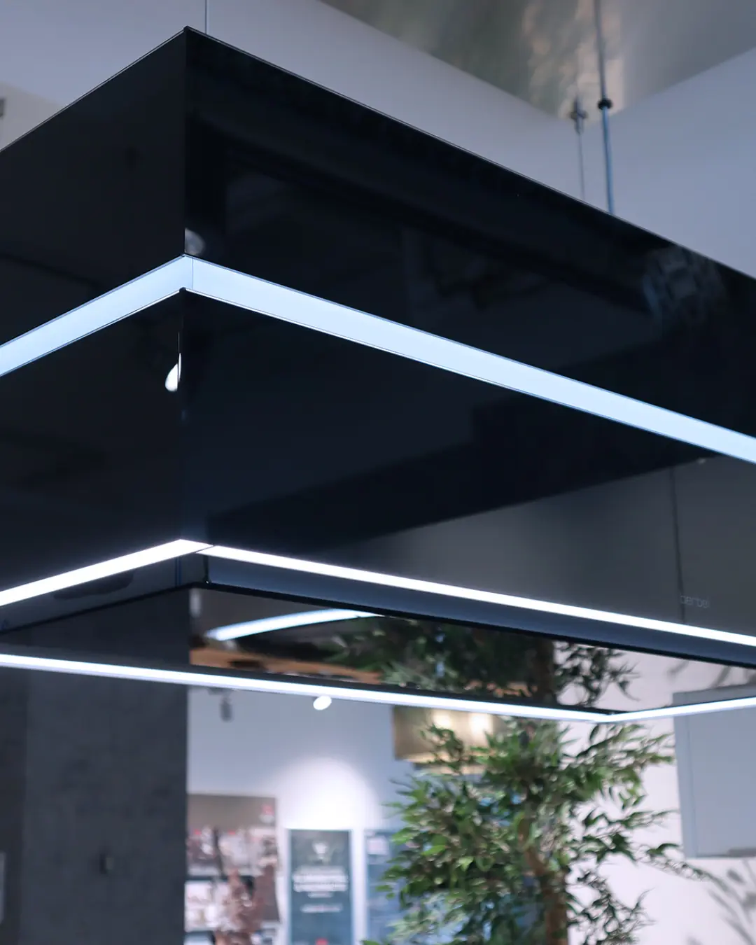 Schwarze Deckenhaube mit umlaufendem LED-Lichtband über der Kücheninsel, Modell Häcker KBK3