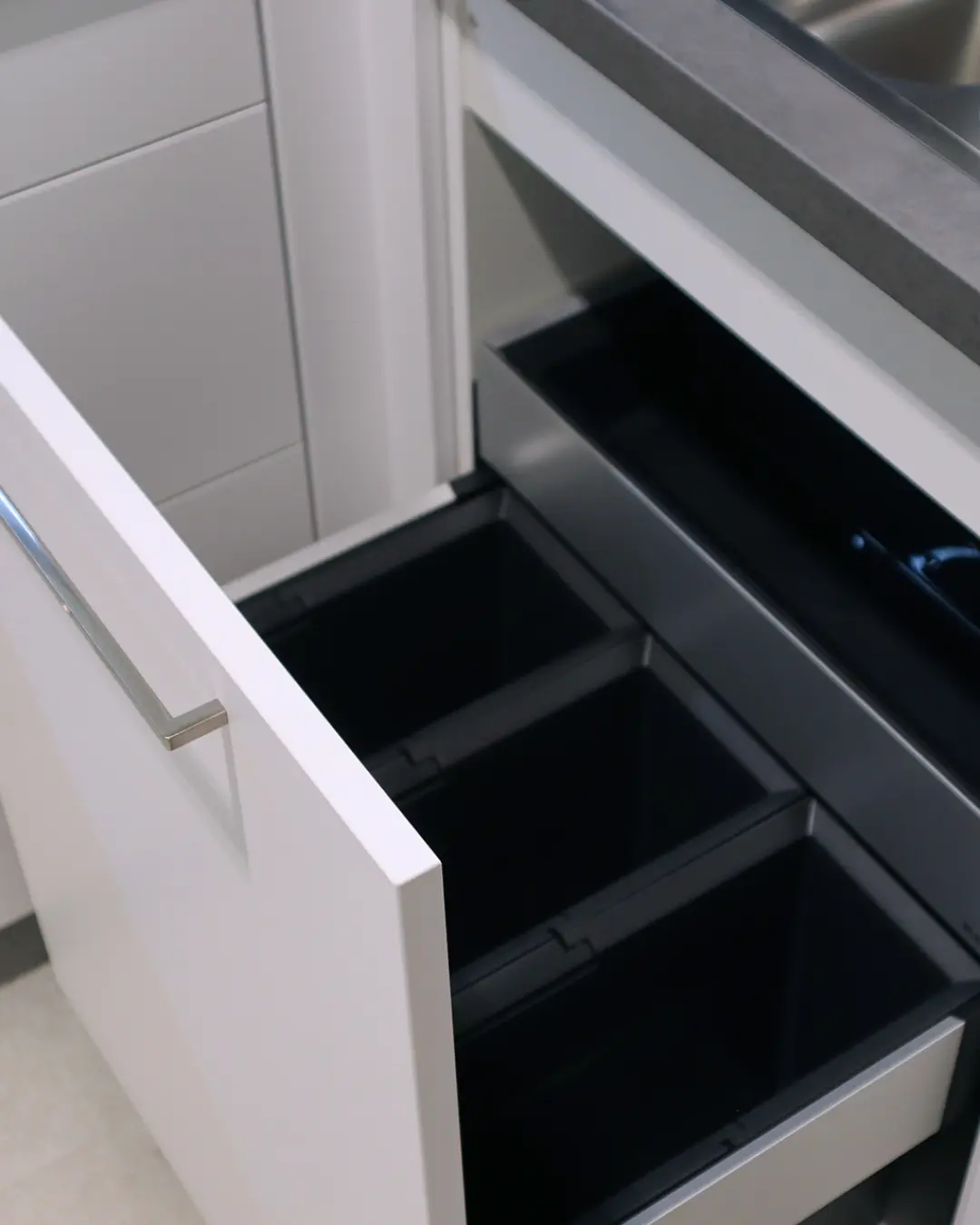 Ausgezogener Auszug mit schwarzem Mülltrennsystem in weißer Nobilia Küche in L-Form