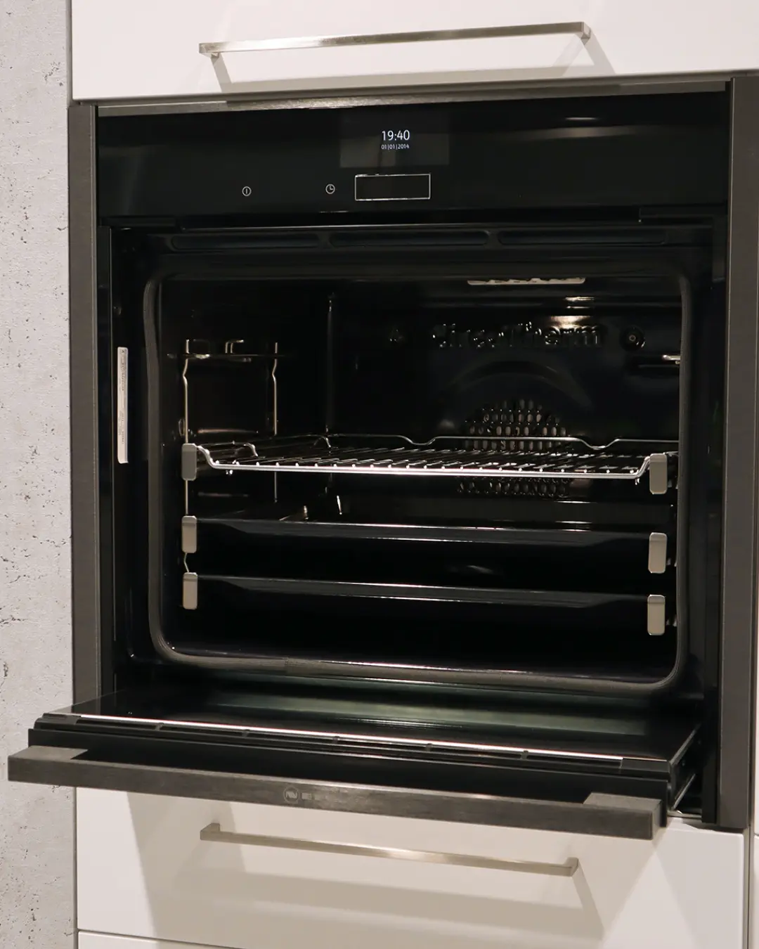 Geöffneter Einbaubackofen mit Display und Rost in der weißen Nobilia Küche in L-Form MGH7