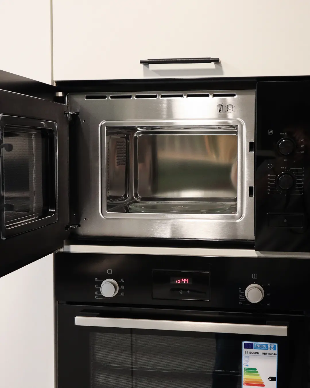 Hochschrank mit geöffneter Einbaumikrowelle und Backofen in weißer Nobilia Küche in U-Form