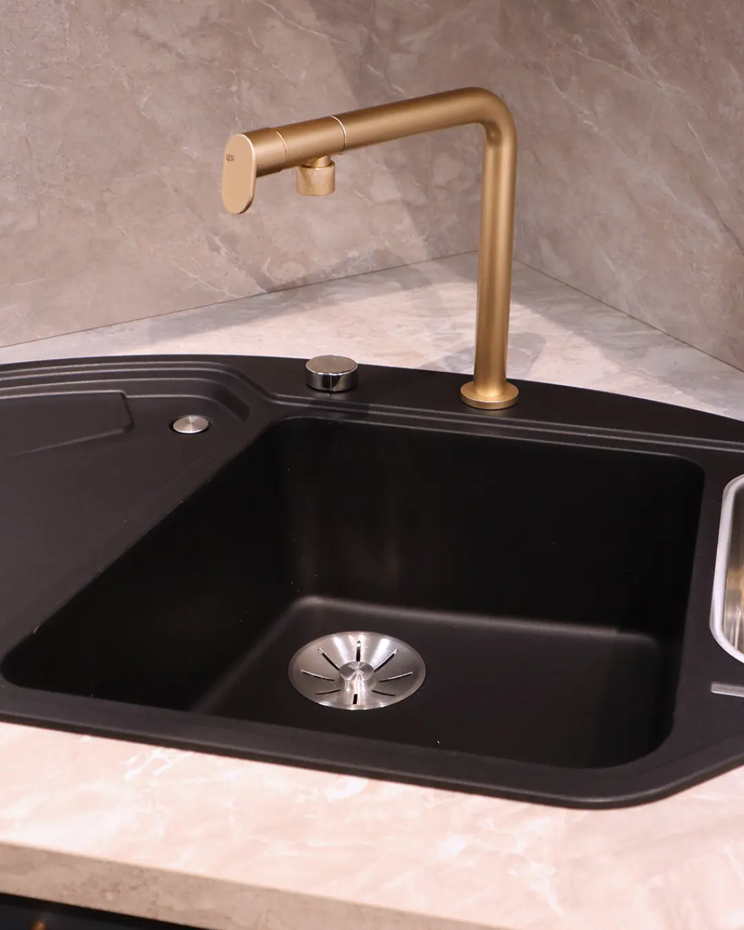 Schwarze Spüle mit goldener Armatur auf Arbeitsplatte in Steinoptik – Detail der fjordblauen Nobilia Küche in L-Form