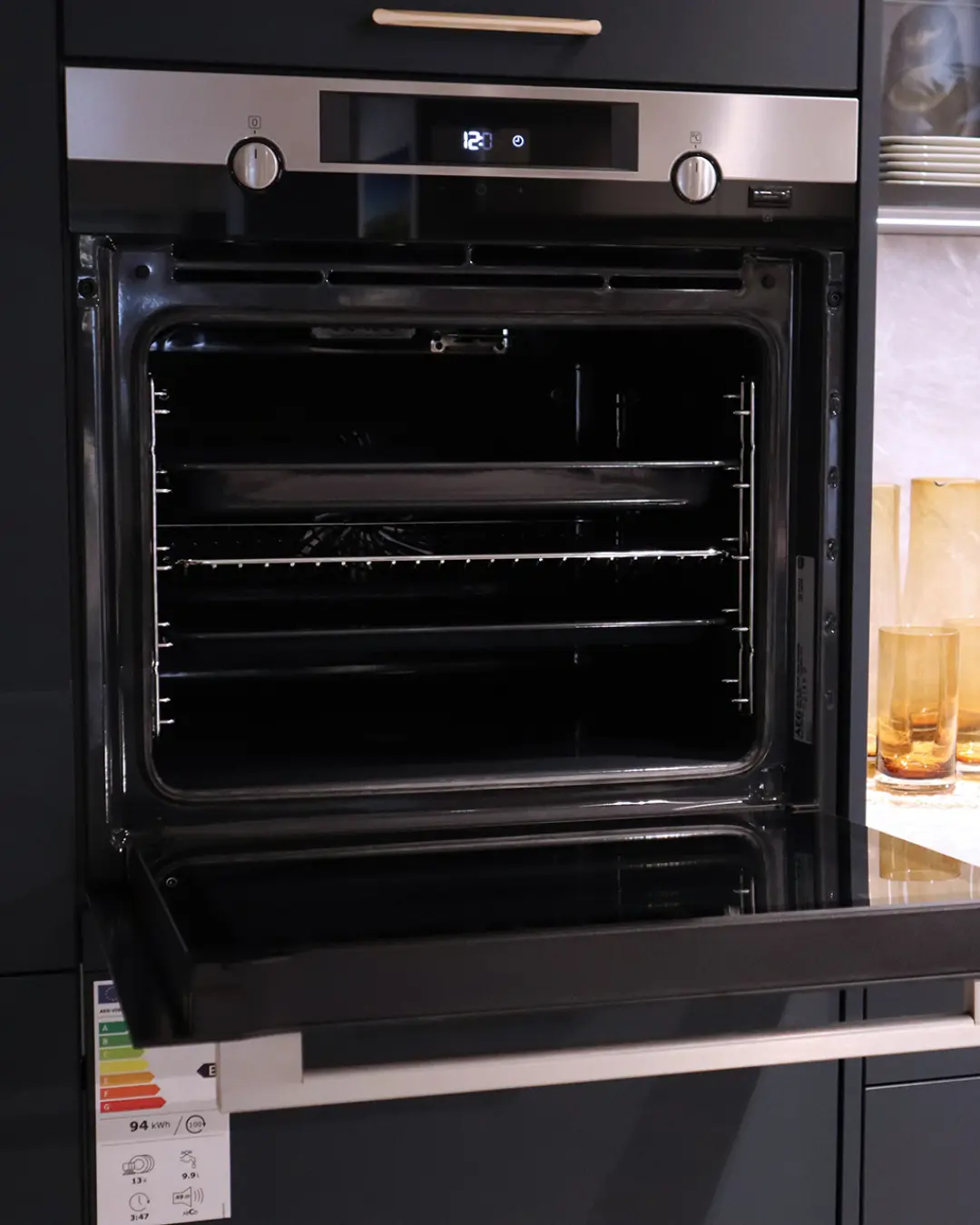 Geöffneter Einbaubackofen mit Display und Einschubgittern in der fjordblauen Nobilia Küche in L-Form