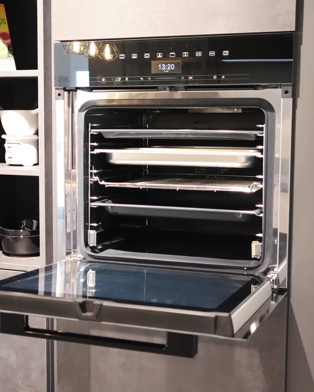 Geöffneter Einbaubackofen mit Touch-Display in der grifflosen grauen Häcker Küche in U-Form