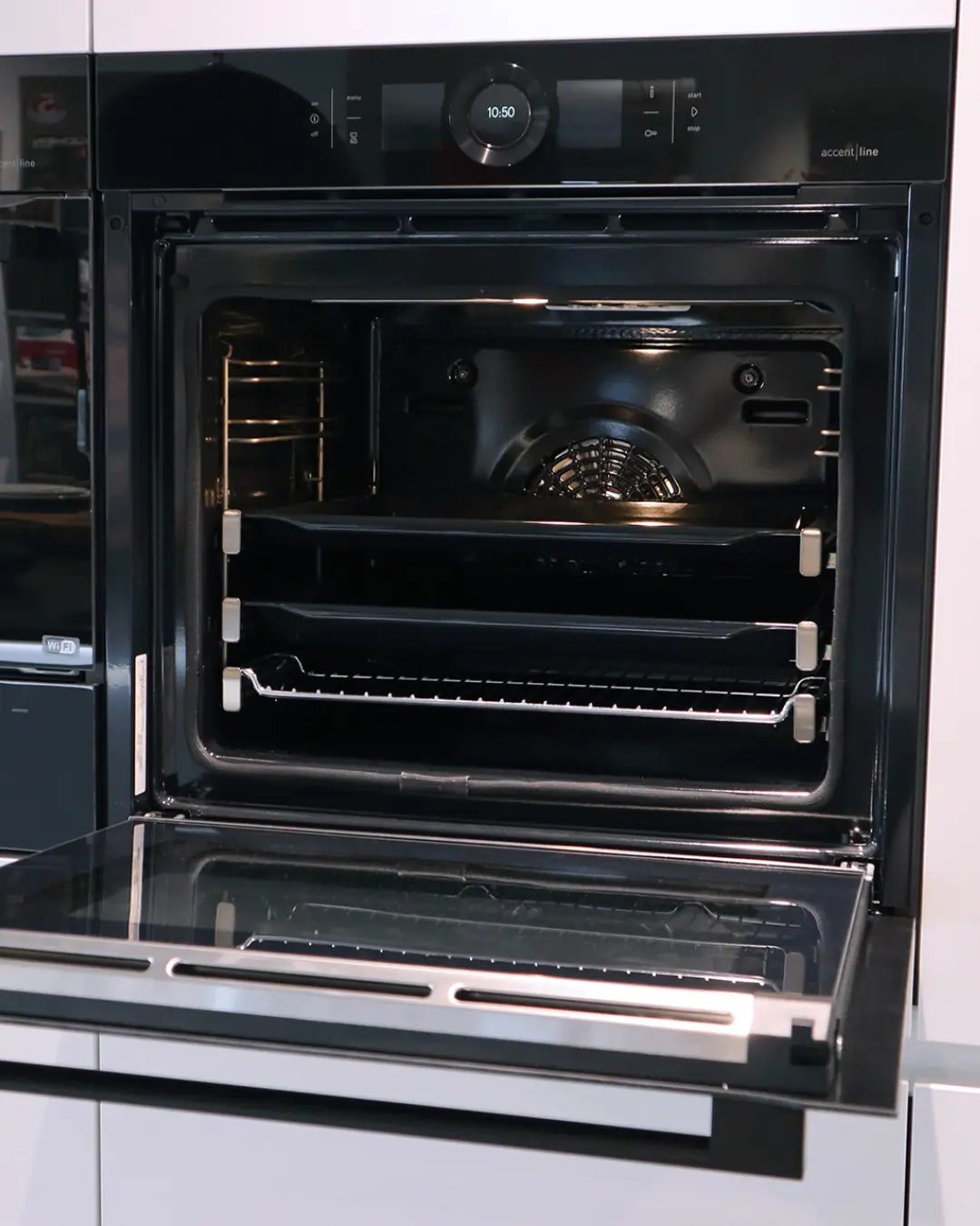 Geöffneter schwarzer Einbaubackofen mit Display in der weißen Häcker Küche KBK1