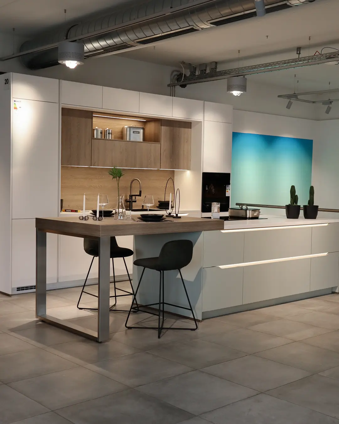 Beige Nobilia Küche KBK20 mit Kochinsel, Theke in Holzoptik und zwei Barstühlen im Studio