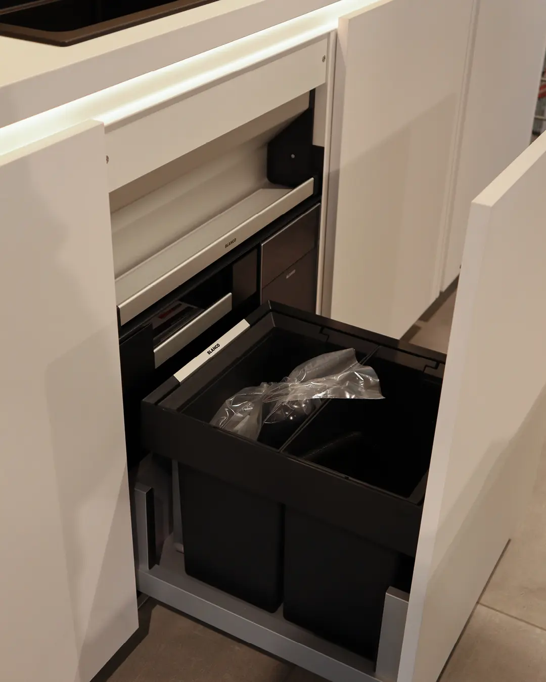 Ausgezogener Abfallauszug mit zwei schwarzen Mülltrennbehältern in einem Unterschrank der Nobilia Küche
