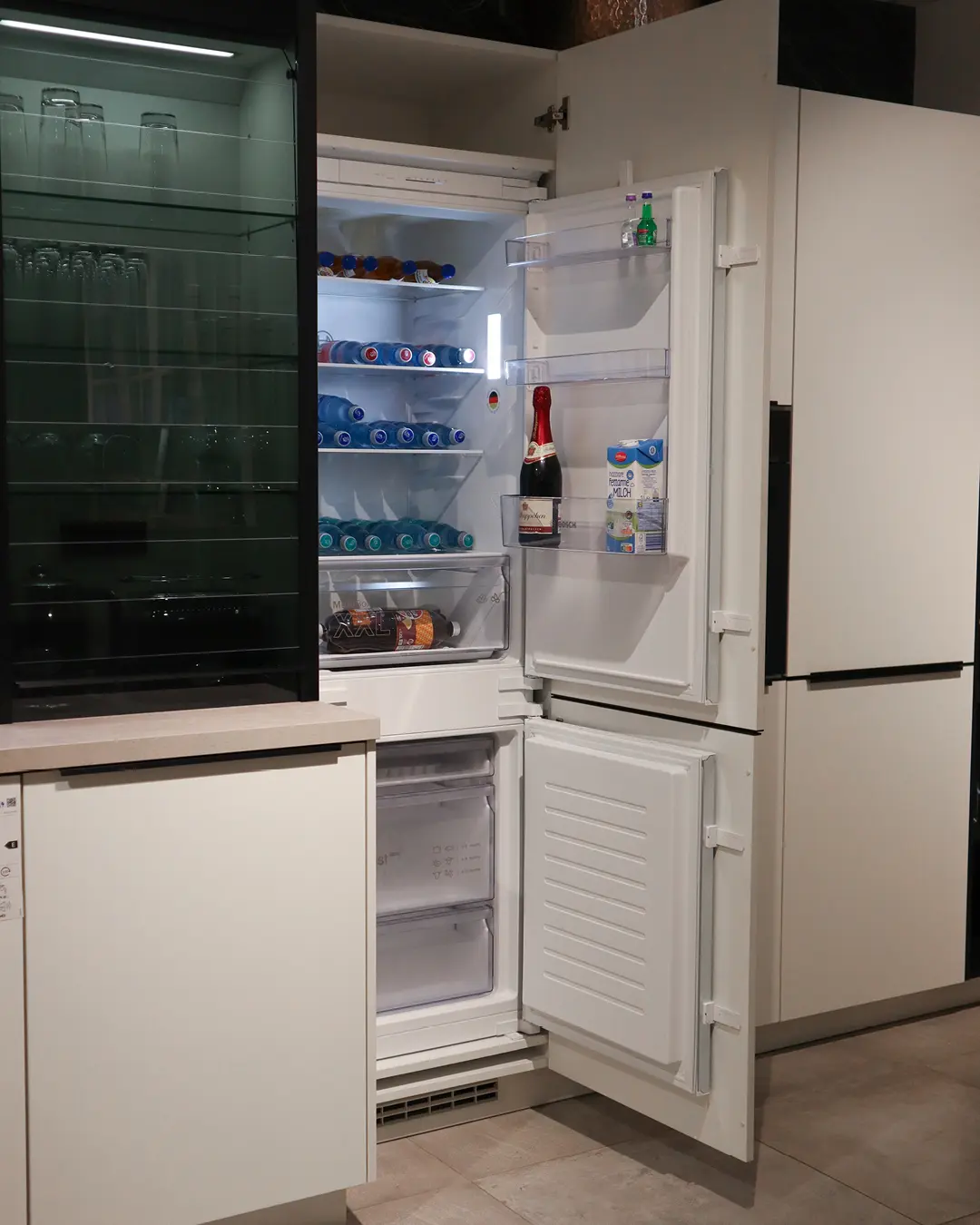 Geöffneter Einbaukühlschrank mit Gefrierfach in weißer Nobilia Küche in L-Form