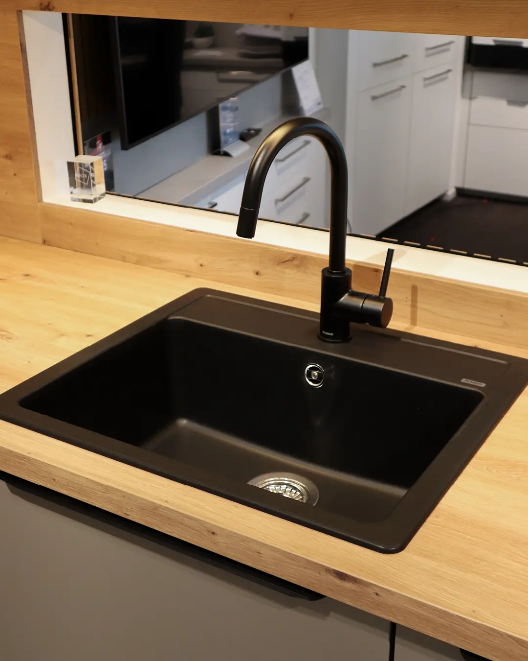 Schwarze Einbauspüle mit hoher schwarzer Armatur in Arbeitsplatte in Holzoptik der grauen Nobilia Küche KBK15