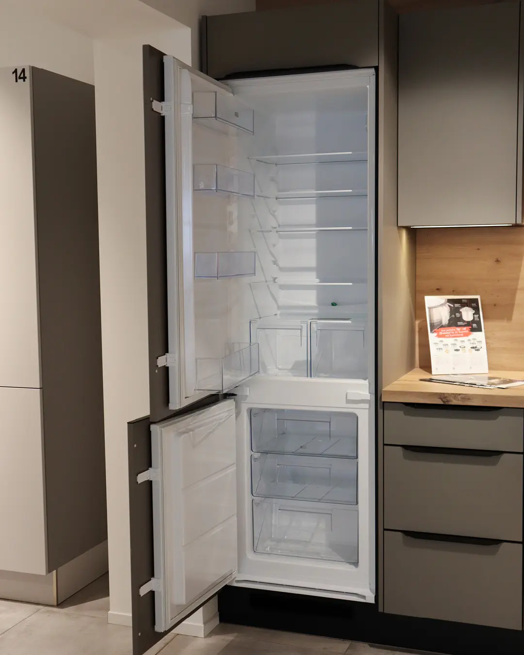 Geöffneter Einbaukühlschrank mit Gefrierfach in grauer Nobilia Küche in L-Form