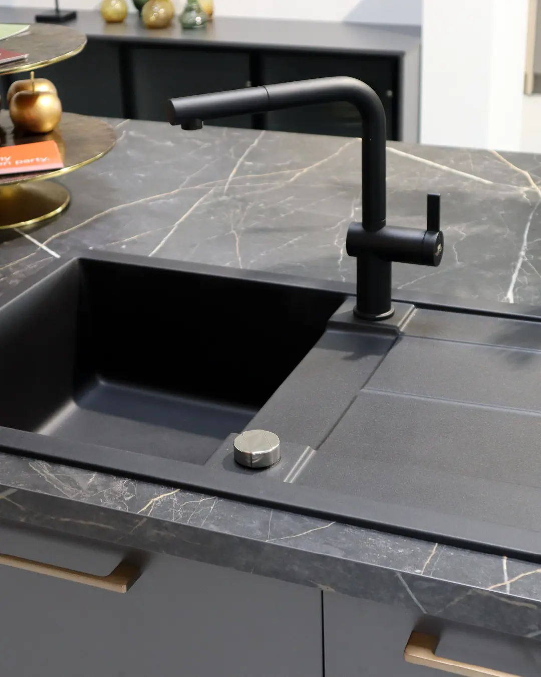 Schwarze Spüle mit Abtropffläche und matter Armatur in der Arbeitsplatte in Marmoroptik der Häcker Küche KFB10 in Graphit