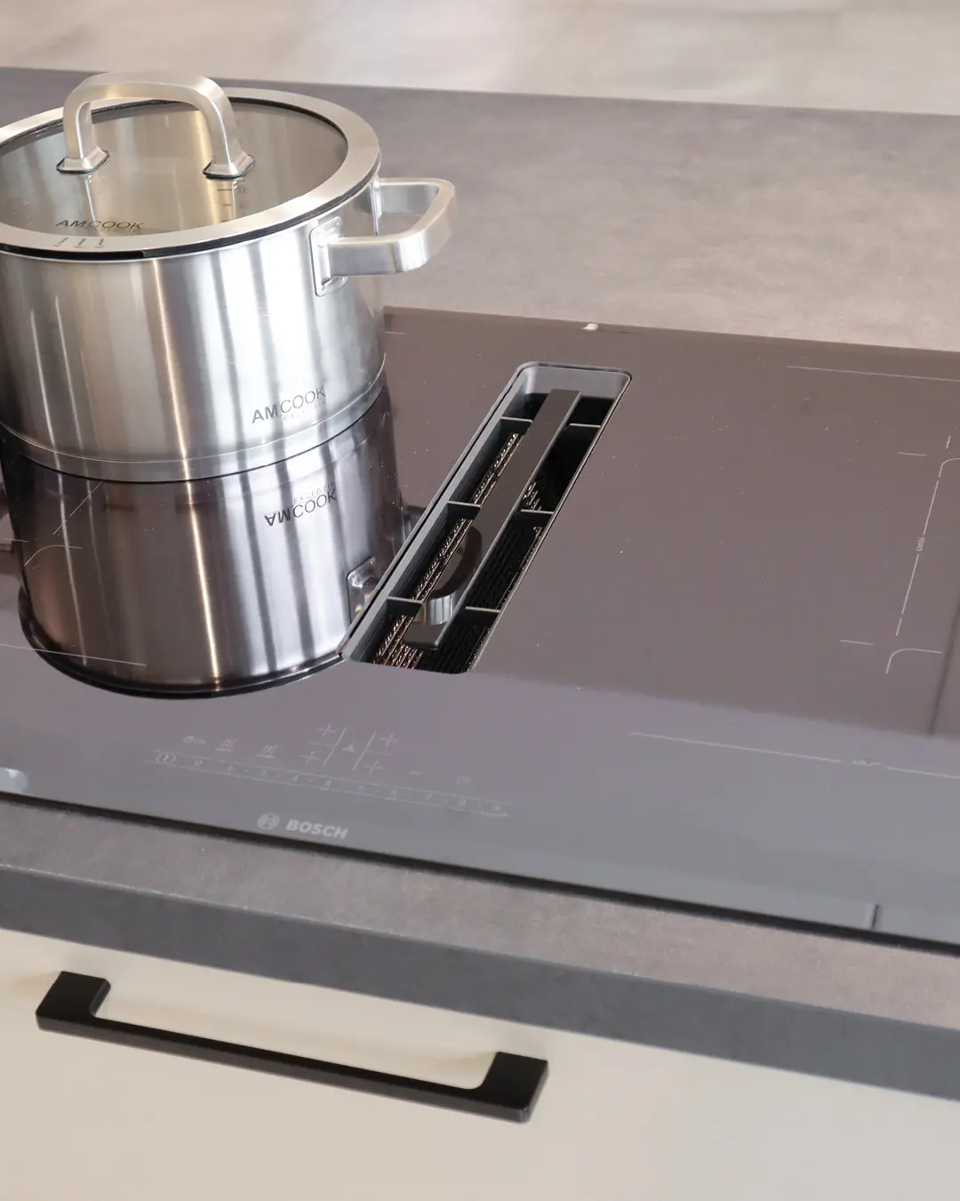 Detail der Häcker Küche in L-Form: Bosch-Kochfeld mit integriertem Muldenlüfter und Edelstahltopf