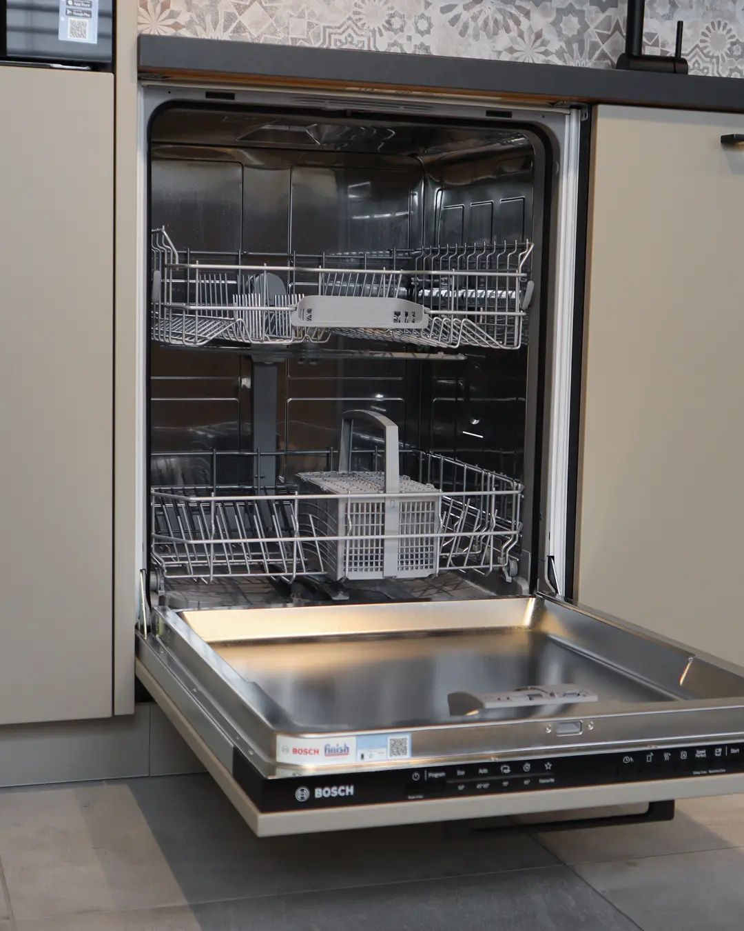 Geöffneter, leerer Bosch Geschirrspüler in beige-brauner Häcker Küche in L-Form