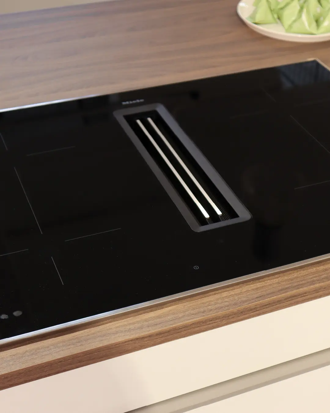 Induktionskochfeld mit integriertem Muldenlüfter von Miele in der Arbeitsplatte in Holzoptik der Häcker Küche KFB5