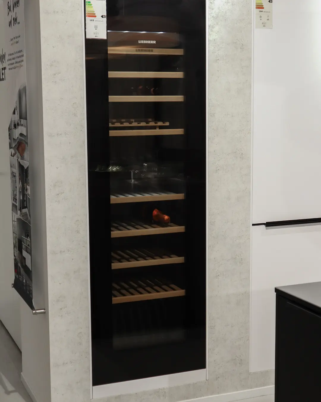 Eingebauter Liebherr Weinschrank mit Glastür und Holzablagen in einer Häcker Küche in Betonoptik