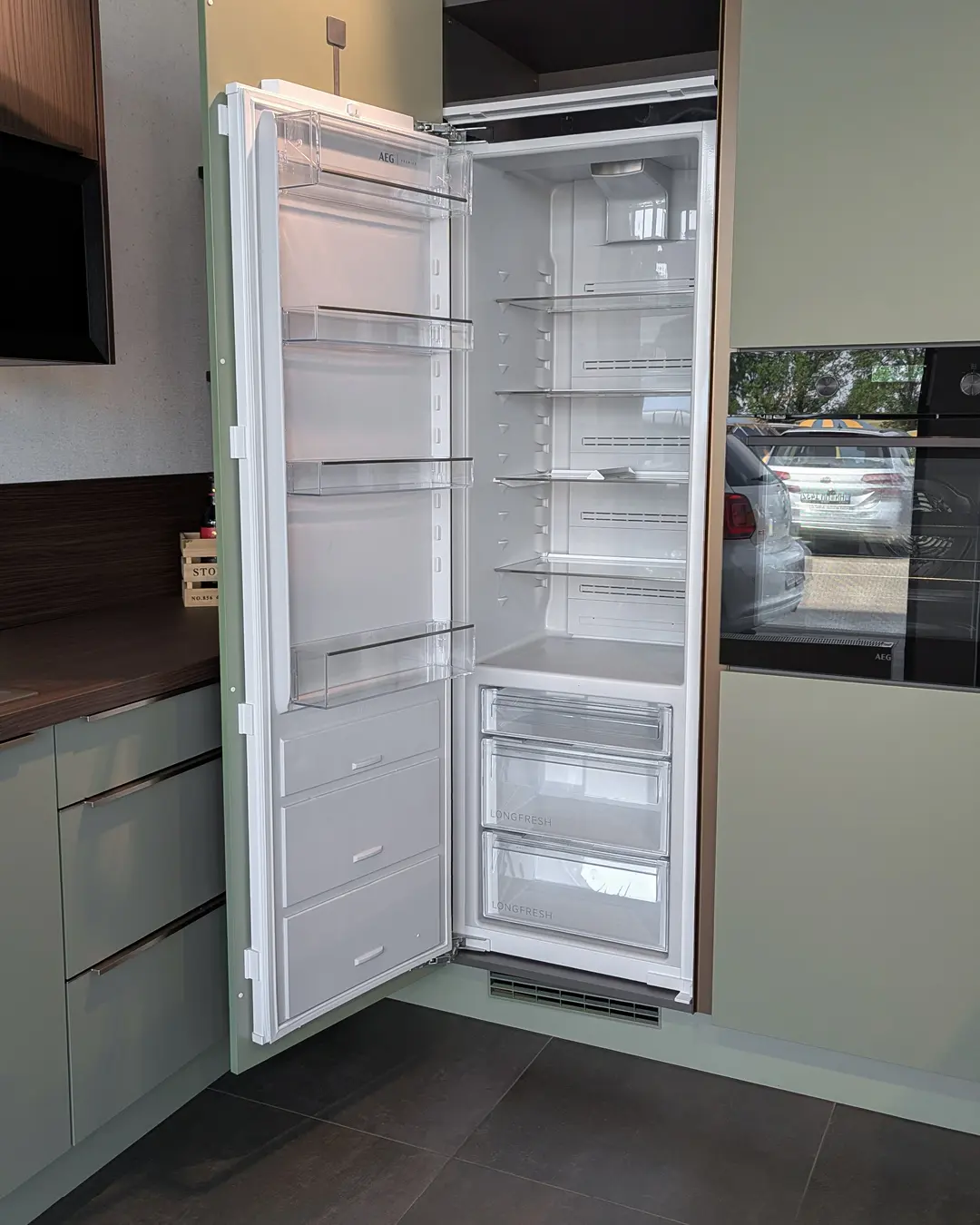 Geöffneter Einbaukühlschrank von AEG in der olivgrünen Nobilia-Küche in U-Form