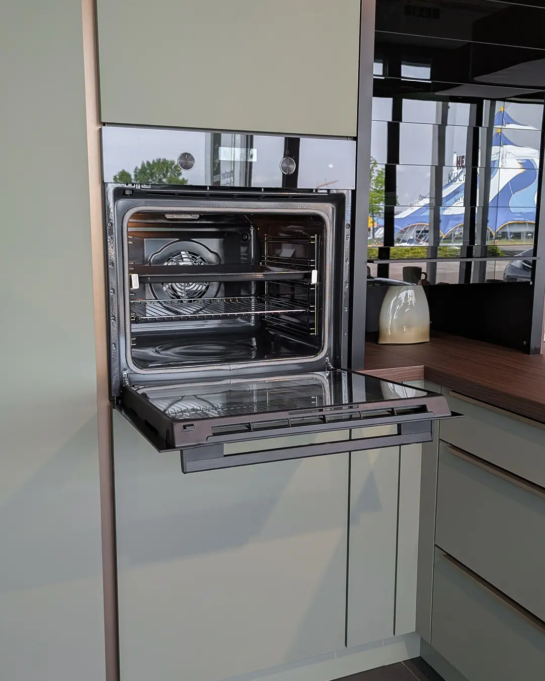 Geöffneter Einbaubackofen in Hochschrank der olivgrünen Nobilia-Küche in U-Form