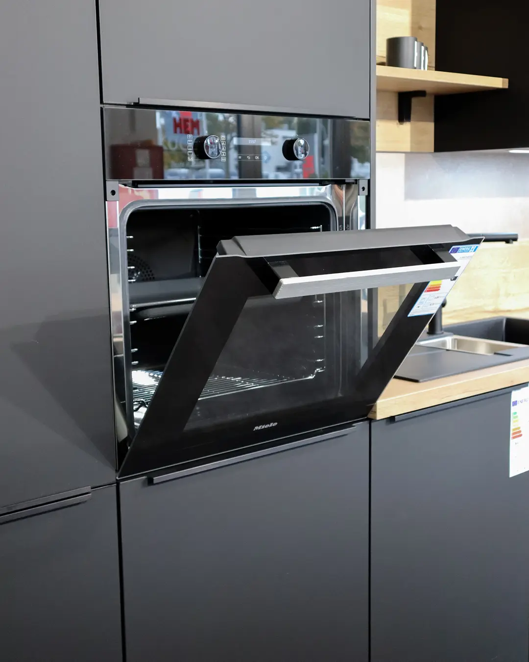 Geöffneter Miele-Backofen in der anthrazitfarbenen Hochschrankfront einer Nobilia Küche